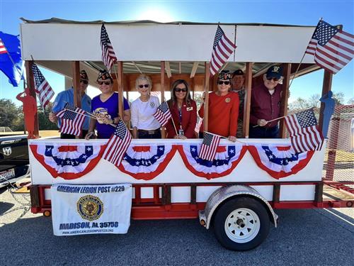 Parade trailer with flag banners carrying veterans